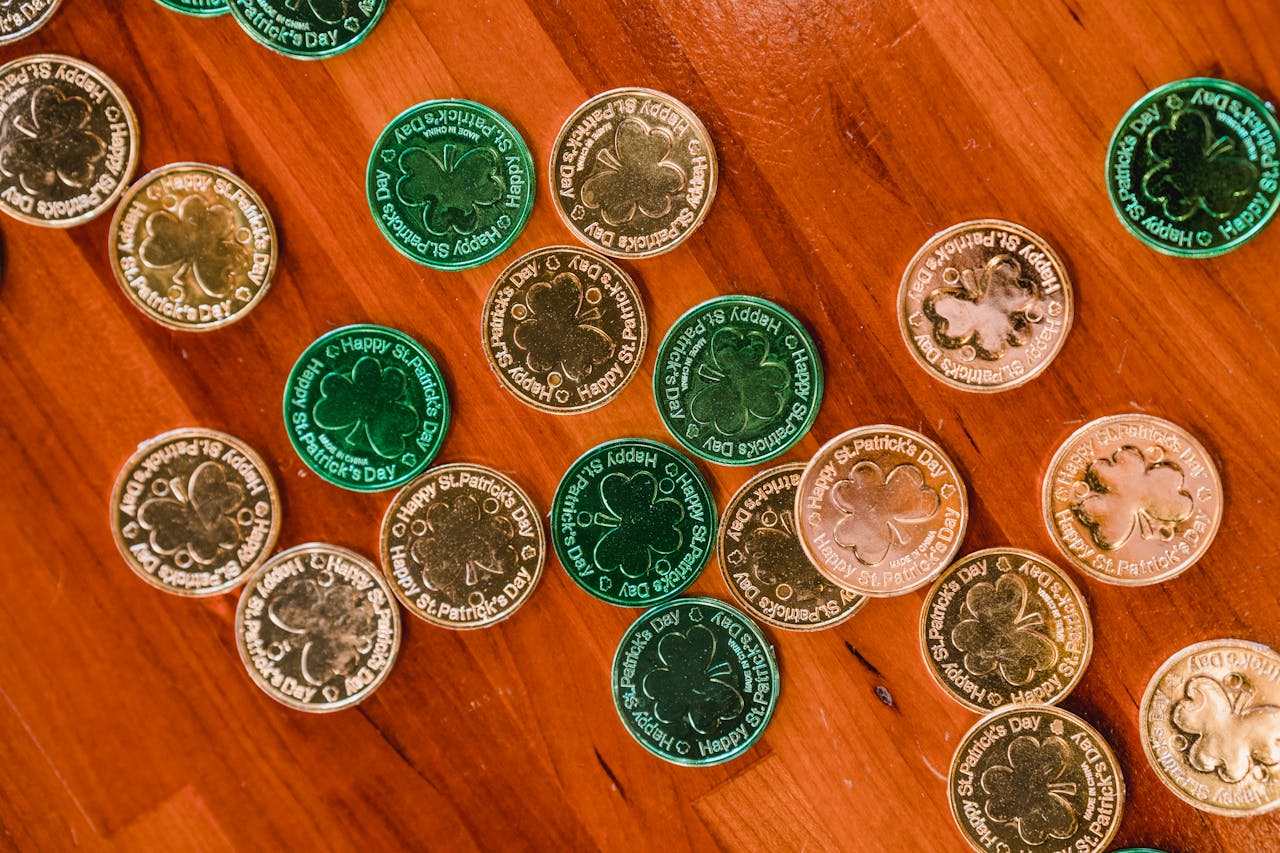 Top view of many sparkling green and golden festive St Patricks day coins placed on timber floor